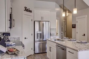 A modern kitchen with white cabinetry, stainless steel appliances, and granite countertops.