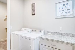 A laundry room with two white washing machines, a granite countertop, and motivational wall art. - Red Coral Retreat near Zion NP, pets welcome (Washington)