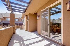 A covered outdoor area with a patio, a sliding glass door leading to a room, and a chair inside. - Red Coral Retreat near Zion NP, pets welcome (Washington)