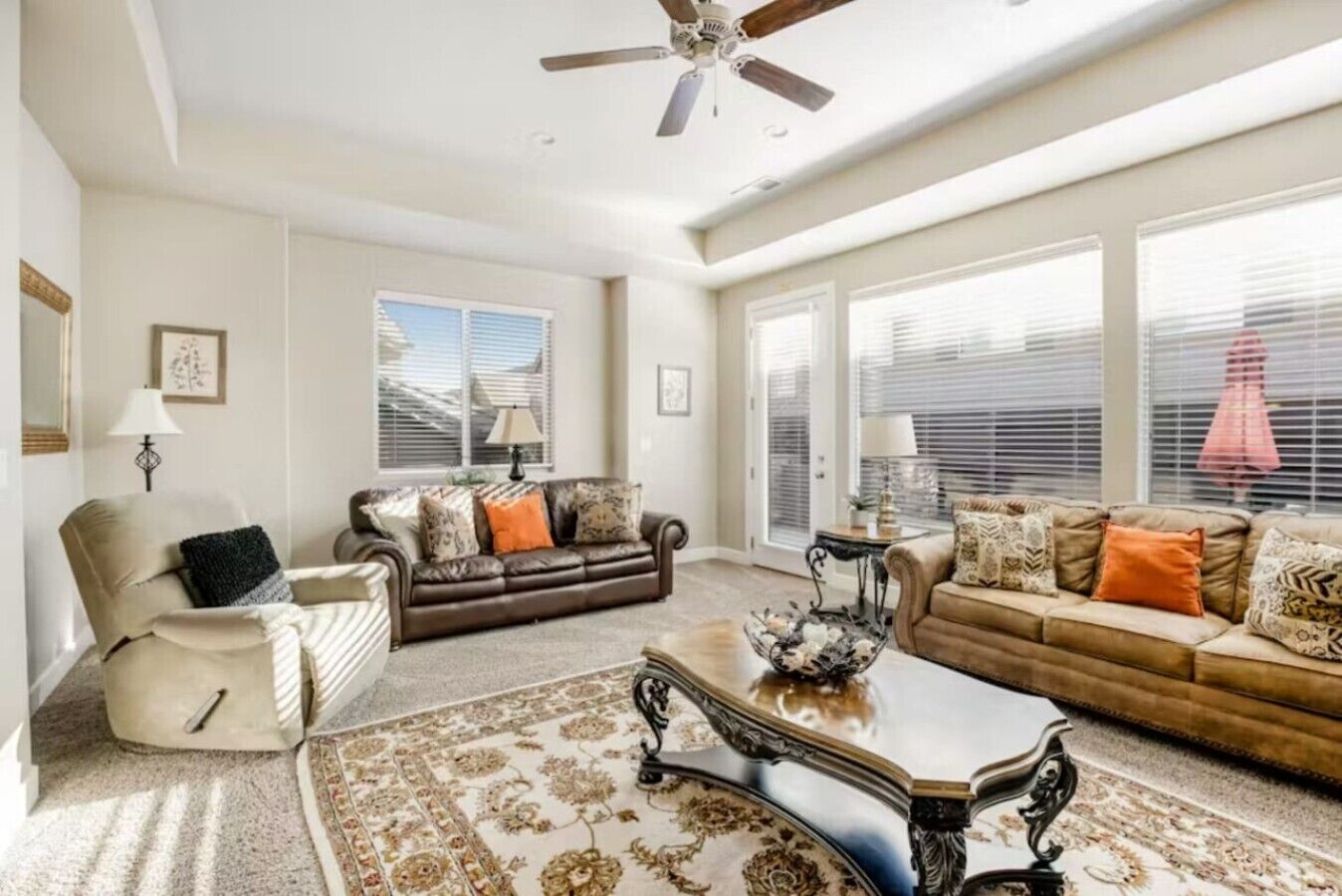 A spacious living room with a ceiling fan, two sofas, a coffee table, and a patterned rug.