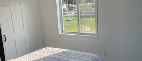 A bedroom with a bed, a window, a door, and a ceiling fan.