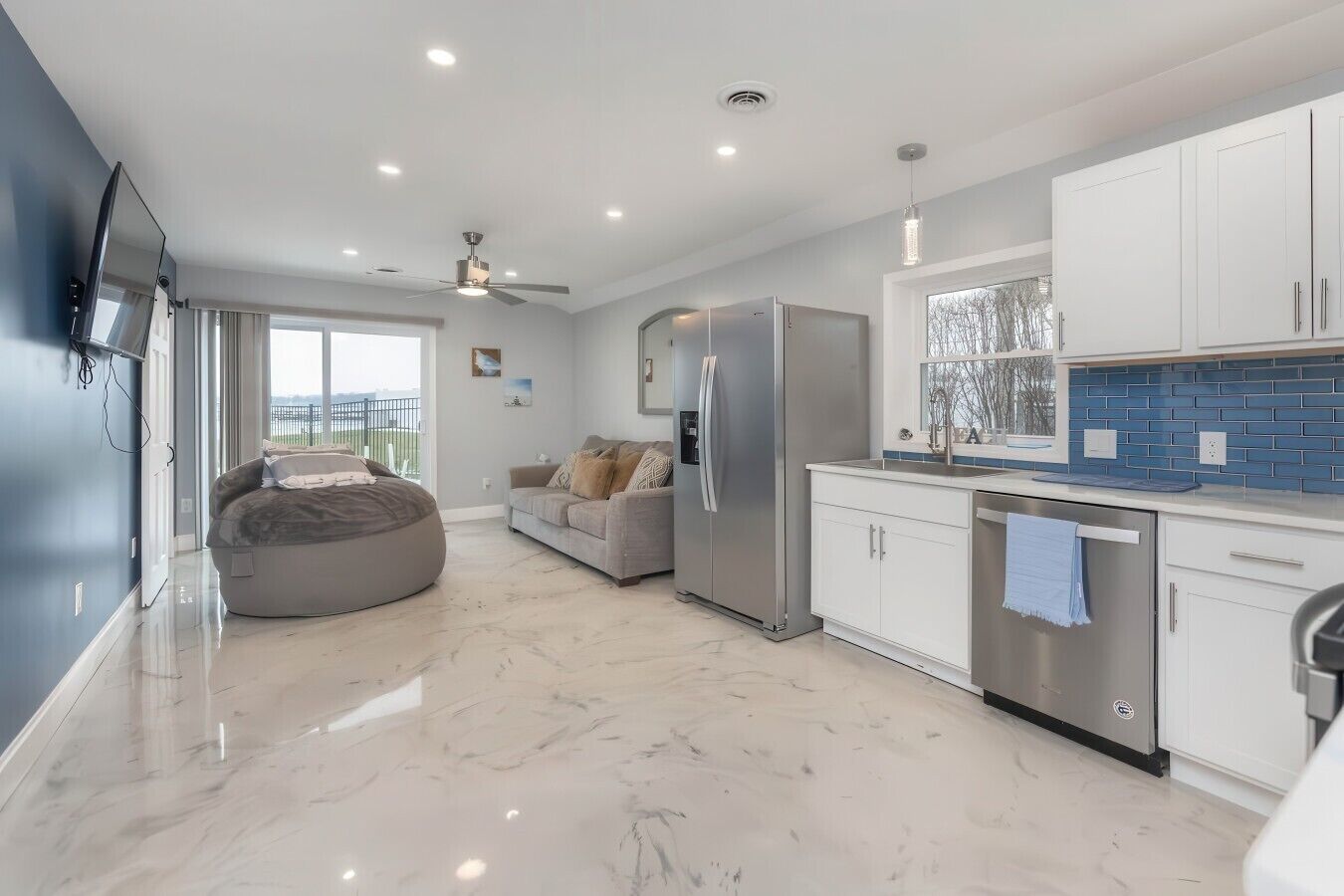A modern kitchen with a built-in refrigerator, white cabinets, and a blue backsplash.