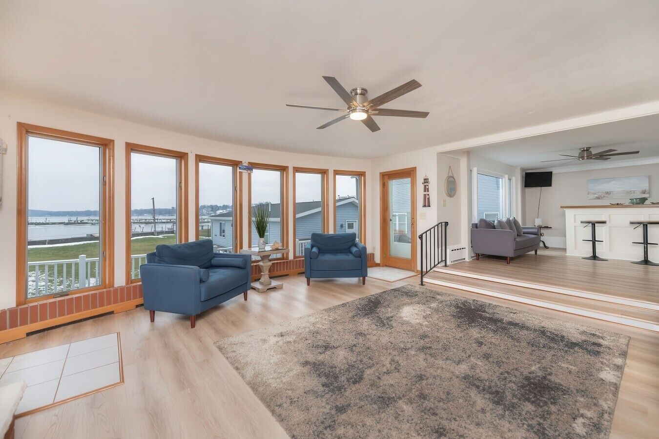 A spacious living area with a large window, a ceiling fan, and a view of the water.