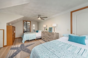 A bedroom with two beds, a dresser, a mirror, a ceiling fan, and a staircase leading to an upper level. - Waterfront Sodus Gem w/ Dock, Game Loft, Bay View (Sodus Point)