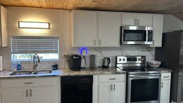 A modern kitchen with white cabinets, a stainless steel microwave, an oven, and a dishwasher.