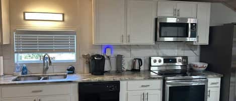 A modern kitchen with white cabinets, a stainless steel microwave, an oven, and a dishwasher.