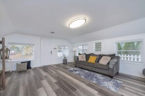 A spacious living area with a grey sofa, a patterned rug, and a ceiling light.