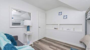 A room with a bed, a bedside table, a mirror, a wardrobe, and a shelf with decorative items.