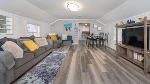 A spacious living area with a gray sofa, a dining table, and a TV stand. - 2BR Shoreside Retreat w/ Beach Access & Interiors (Rochester)