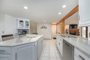 A modern kitchen with white cabinetry, a central island, and a built-in oven. - Waterfront Sodus Gem w/ Dock, Game Loft, Bay View (Sodus Point)