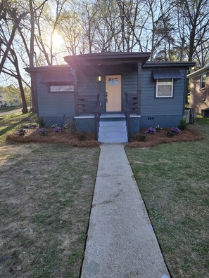 A small, single-story building with a front door, a small porch, and a concrete pathway leading to the entrance. - Modern 2BR Retreat Near Downtown Birmingham (Birmingham)