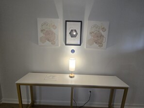 A room with a white desk, a framed artwork above it, and a lit table lamp. - Modern 2BR Retreat Near Downtown Birmingham (Birmingham)