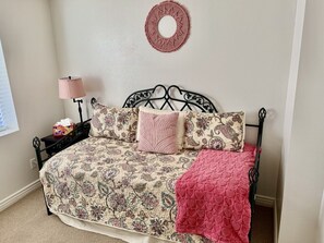 Un dormitorio con cama, mesita de noche, lámpara y un adorno en la pared.