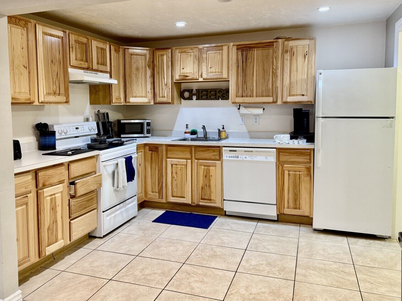 A kitchen with wooden cabinets, a white stove, a microwave, a dishwasher, and a refrigerator.