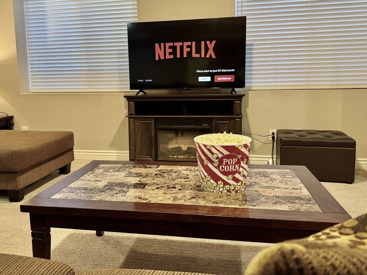 A living room with a television displaying 'NETFLIX' and a popcorn bucket on a coffee table.