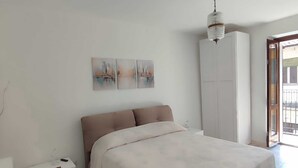 Un dormitorio con cama, armario, mesita de noche y una obra de arte en la pared.