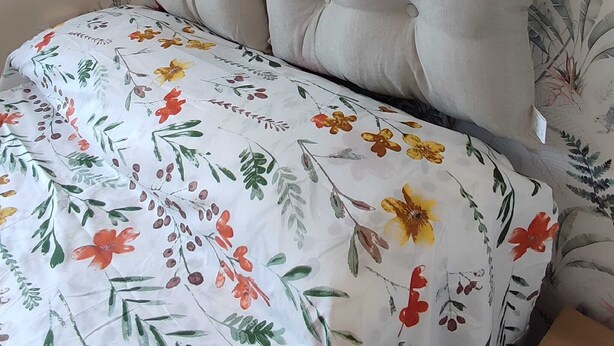 Una cama con una colcha estampada con motivos florales y un cabecero con diseño de hojas.