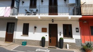 Un edificio de dos plantas con un balcón, una puerta y un letrero de estacionamiento.