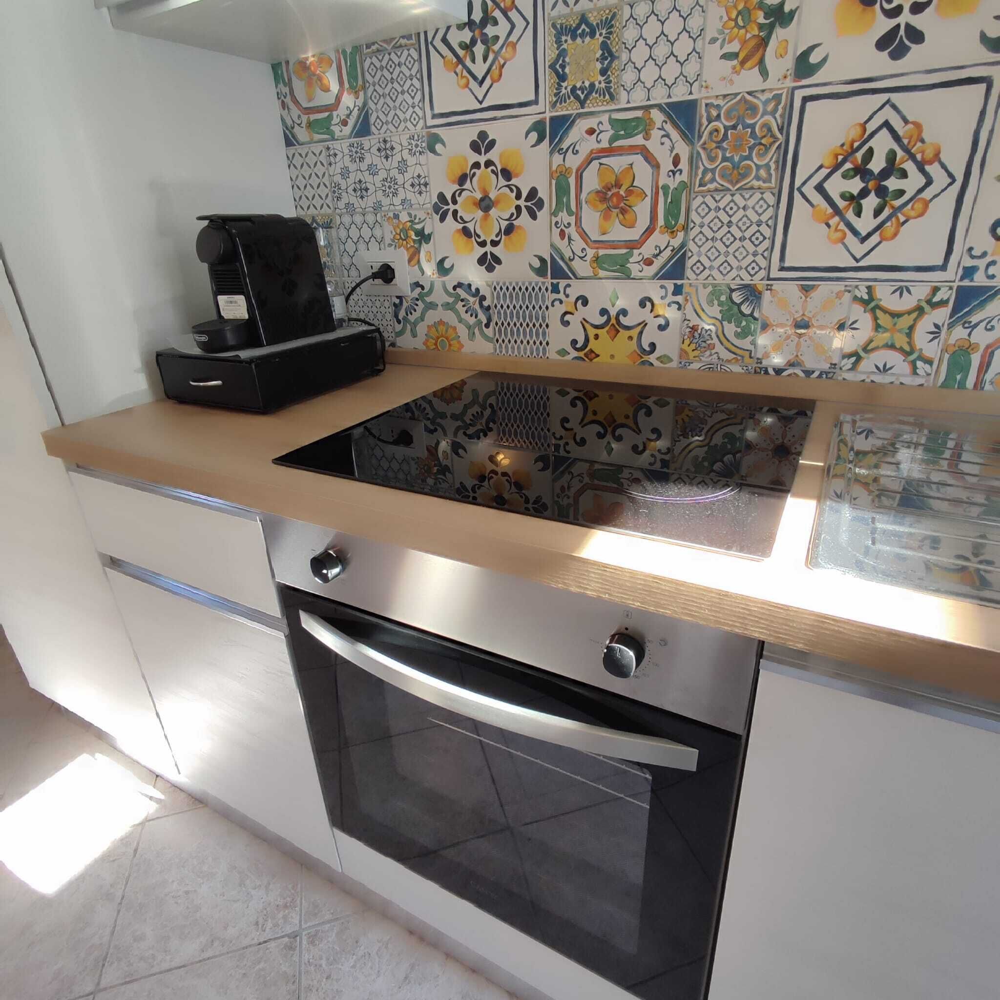 Une cuisine au design moderne, dotée d’un four en acier inoxydable et d’une machine à café posée sur le plan de travail.