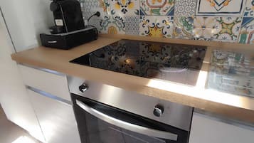 Une cuisine au design moderne, dotée d’un four en acier inoxydable et d’une machine à café posée sur le plan de travail.