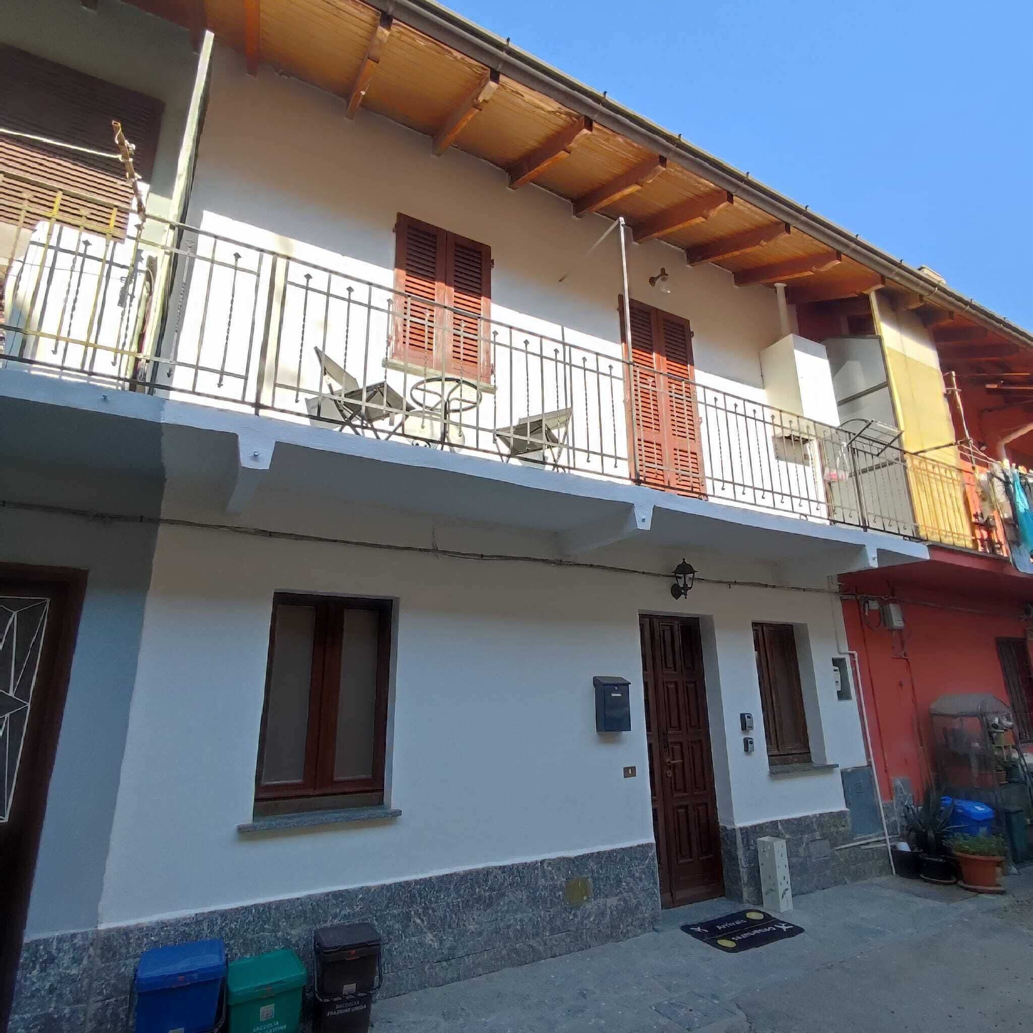 Un bâtiment à deux étages doté d’un balcon, d’une porte et d’un petit espace extérieur aménagé pour s’asseoir.
