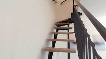 Un escalier avec une rampe en bois et un luminaire fixé au mur.