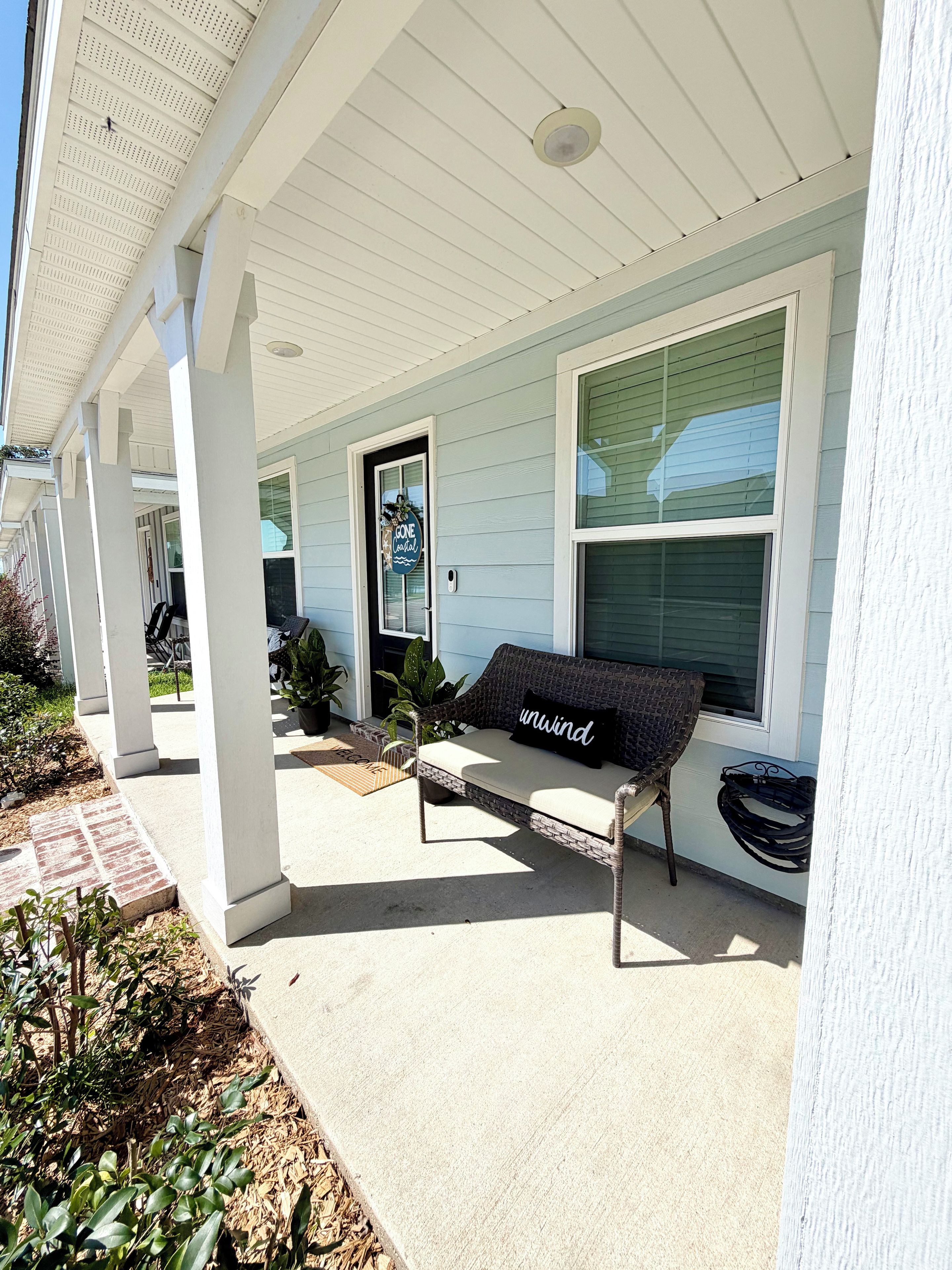 A covered porch with a bench and a welcome sign.