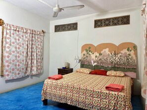 A bedroom with a bed, a ceiling fan, a wall-mounted lamp, and a decorative headboard. - Conner House (Brisas de Zicatela)