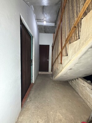A narrow hallway with a wooden door on the left and a partially constructed wall on the right. - Conner House (Brisas de Zicatela)