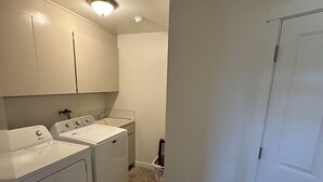 Una sala de lavandería con dos lavadoras, un secador y un lavabo.
