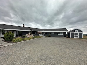 A two-story house with a gravel driveway and a small shed.