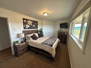 A bedroom with a bed, bedside tables, a lamp, a painting, a TV, and a window with a view. - 3 Bedroom Farmhouse with great central location and ease of travel. (Snohomish)