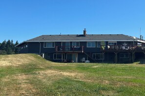 A two-story building with a flat roof, large windows, and a covered outdoor area with chairs and a table. - 3 Bedroom Farmhouse with great central location and ease of travel. (Snohomish)