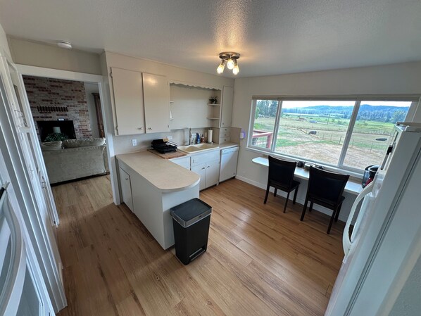 Une cuisine moderne dotée d’une grande fenêtre, d’un plancher en bois et offrant une vue sur un paysage rural.