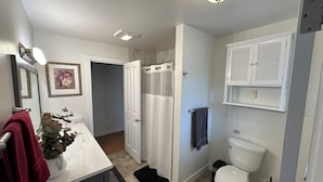Une salle de bain équipée de toilettes, d’un rideau de douche et d’un lavabo avec un porte-serviettes.