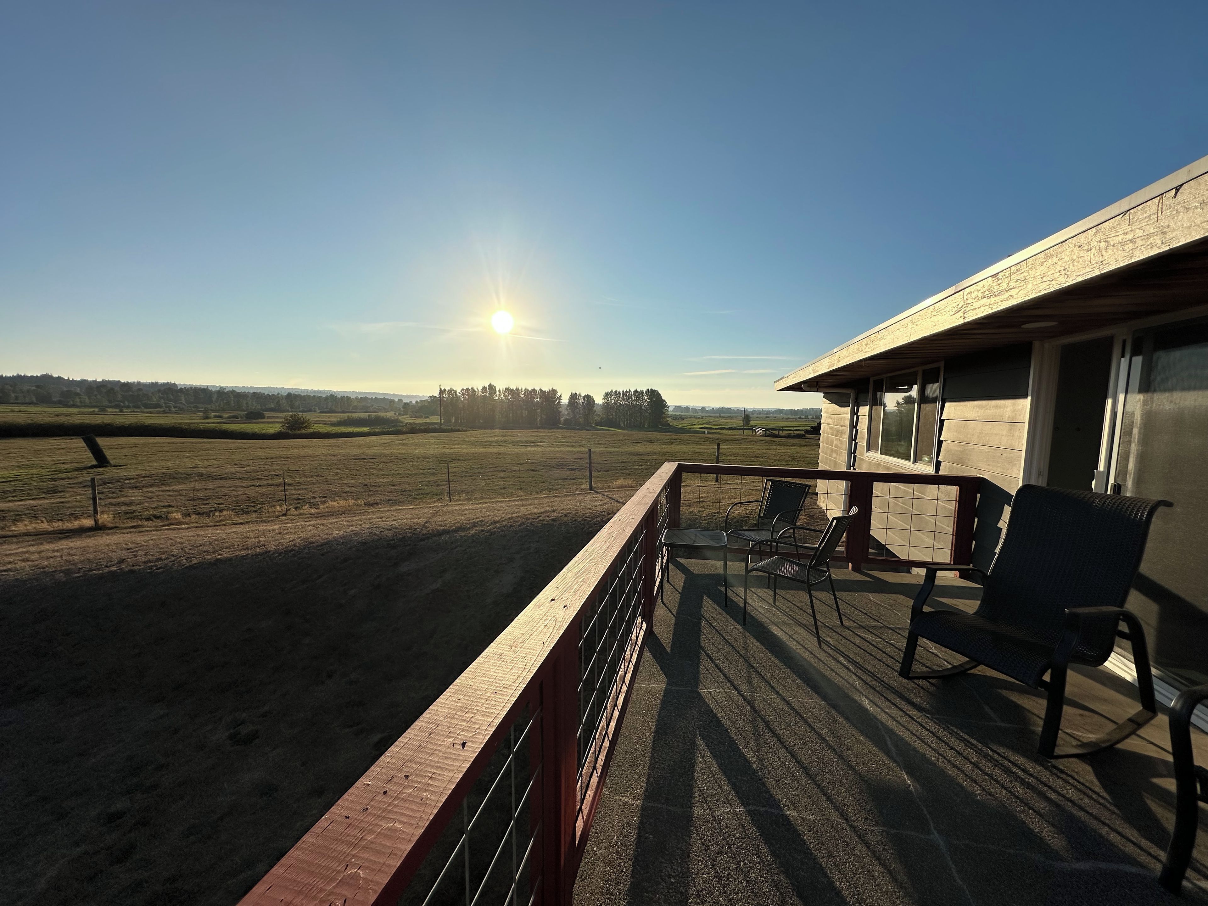 A balcony with a view of a field and a building.