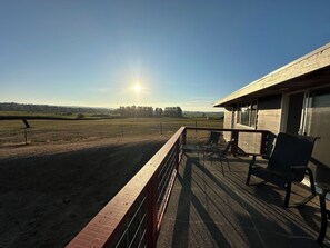 A balcony with a view of a field and a building.