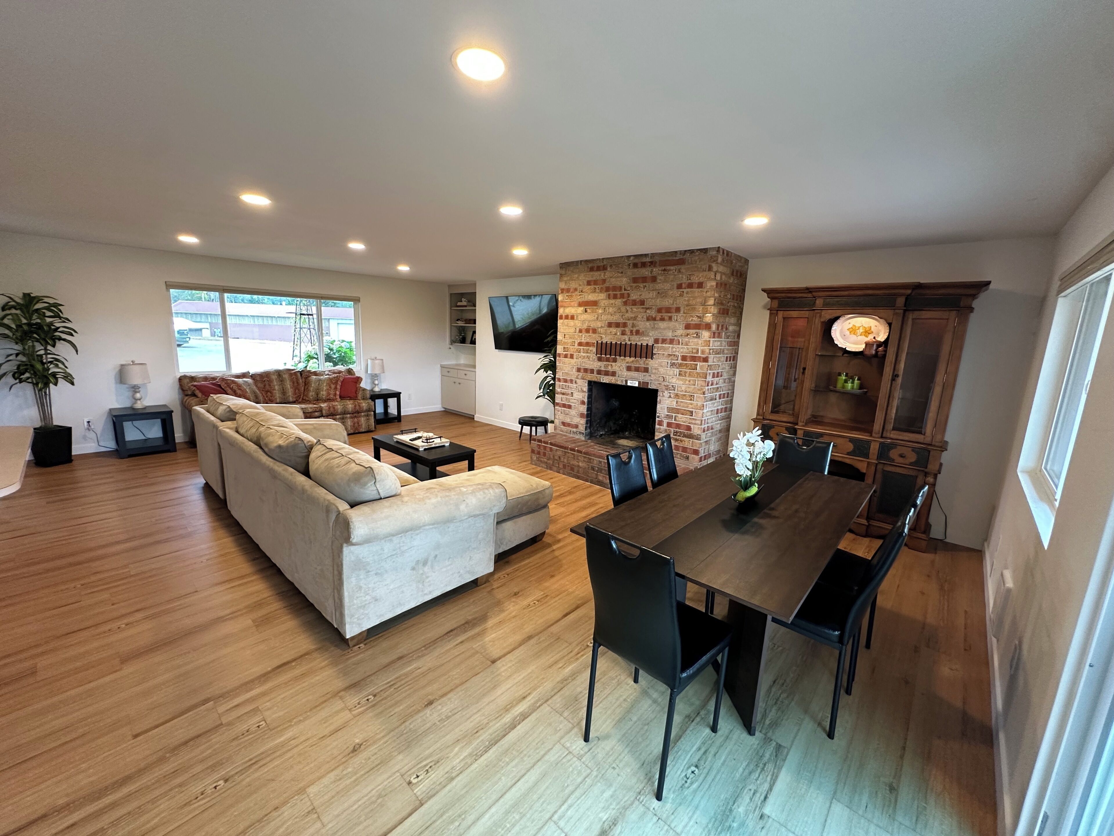 A spacious living area with a sofa, dining table, and a brick fireplace.