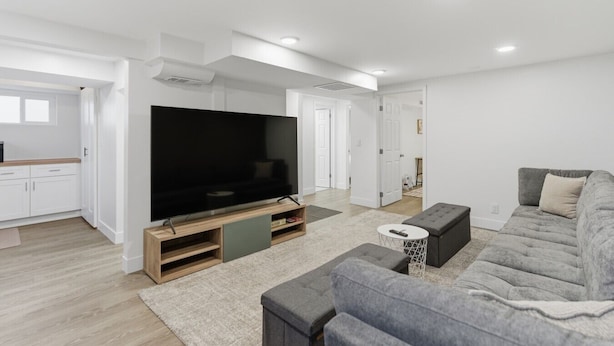 Un salon moderne avec un grand téléviseur à écran plat, un canapé gris et une petite table basse ronde.