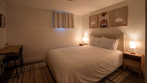Une chambre d’hôtel avec un lit, des tables de chevet, un bureau et une chaise.