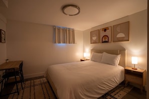 Una habitación de hotel con una cama, mesitas de noche, un escritorio y una silla.