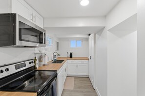 Una cocina moderna con armarios blancos, microondas integrado, estufa y cafetera.