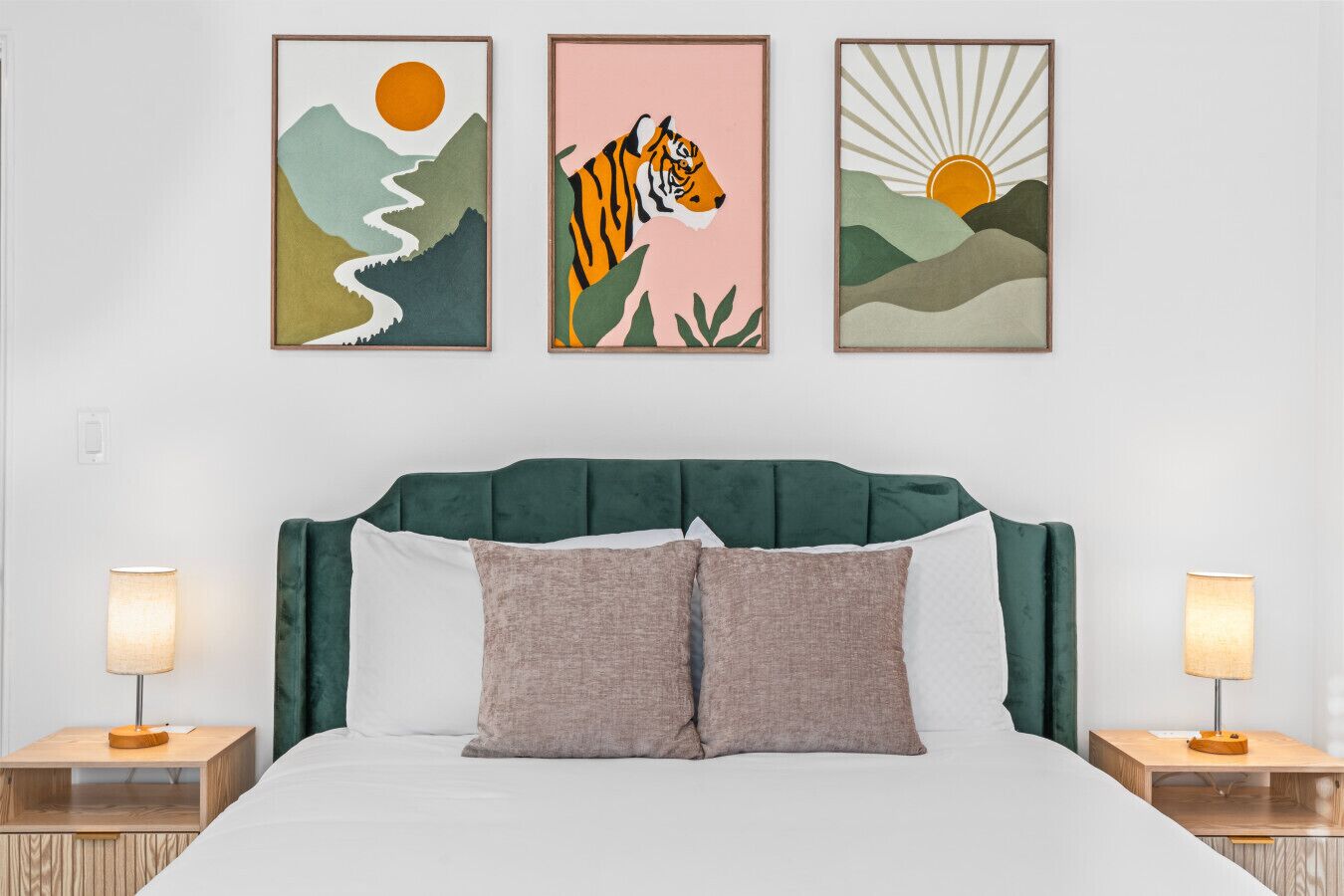 Un dormitorio con una cama, dos mesitas de noche y tres cuadros enmarcados en la pared.