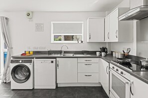 A modern kitchen with a built-in washer, oven, and dishwasher. - Modern 3BR Home Perfect for Groups and families (Little Hulton)
