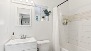Bagno con lavandino bianco, specchio, WC e zona doccia.
