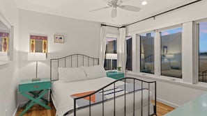 A bedroom with a bed, a nightstand, a ceiling fan, and a window with curtains. - Matarangi by Avantstay Gulf-front Grayton Beach Retreat Pool + Golf Cart Near Gulf Place (Santa Rosa Beach)