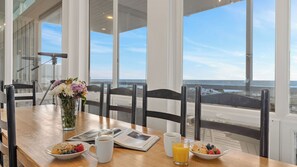 Ein Frühstückstisch mit Blick auf das Meer, eine Blumenvase und eine Zeitung.