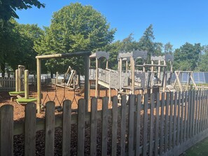 A playground with wooden structures and a fence. - Luxury caravan on a 5 star holiday park (Llanrug)