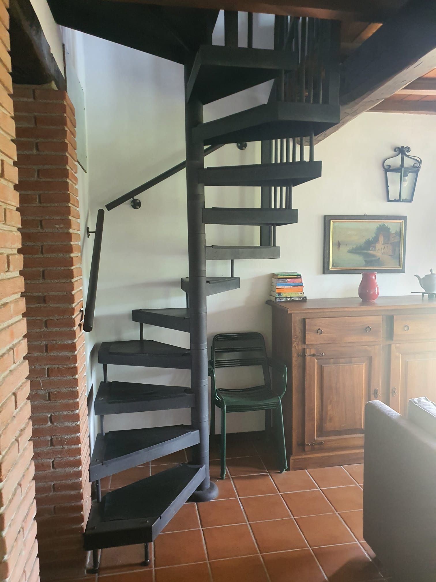 Una escalera de caracol con una pared de ladrillo a un lado y un suelo de baldosas.