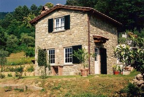 A stone house with a two-story structure, a front door, and windows with shutters. - In the Heart of Nature (Pescia)